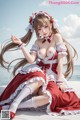 A woman in a red and white dress sitting on a beach.