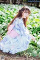 A woman in a blue and pink kimono sitting in a field of flowers.