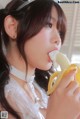 A woman in a white dress eating a banana.