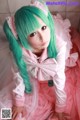 A woman with long green hair wearing a pink dress.