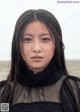 A woman with long black hair standing on a beach.