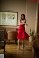 A woman in a red dress dancing in a living room.