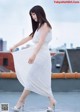 A woman in a white dress is walking on a rooftop.