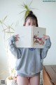 A woman holding up a book in front of her face.