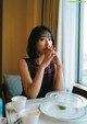 A woman sitting at a table with a cup of coffee.