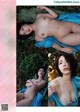 A naked woman laying on a blanket in the grass.